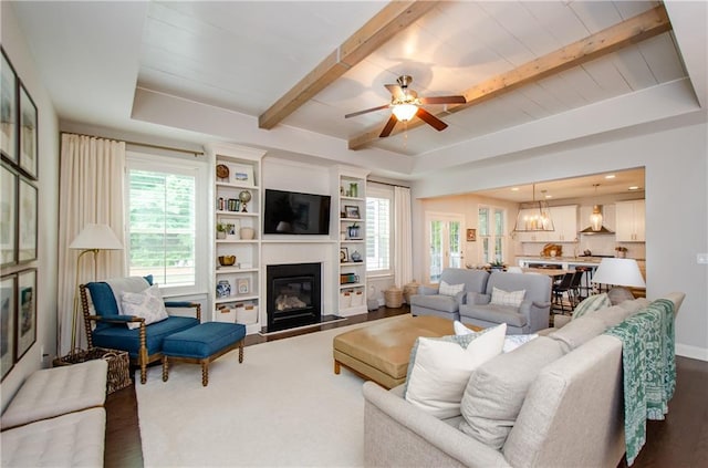 2535 Castlerock Ct, Cumming, GA 30041 - living area featuring wood finished floors, plenty of natural light, a glass covered fireplace, ceiling fan, and beam ceiling