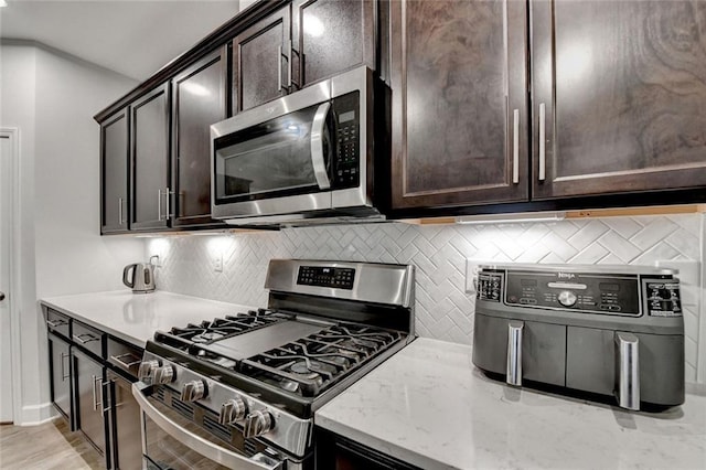811 Pineberry Ct, Grayson, GA 30017 - kitchen featuring stainless steel appliances, dark brown cabinetry, tasteful backsplash, light stone countertops, and baseboards