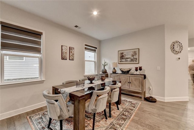 dining room featuring light wood finished floors, visible vents, and baseboards