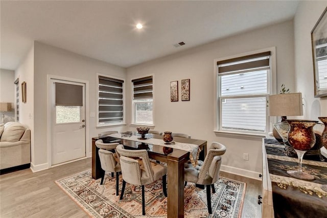 dining area featuring baseboards, light wood-style flooring, visible vents, and a wealth of natural light