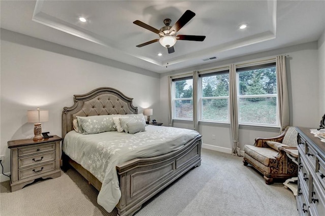 bedroom featuring light carpet, visible vents, a tray ceiling, and baseboards