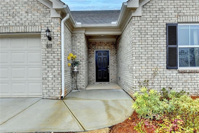 property entrance with a garage, a shingled roof, and brick siding