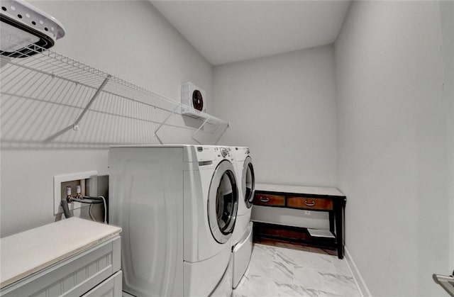 washroom featuring washing machine and dryer, marble finish floor, baseboards, and laundry area