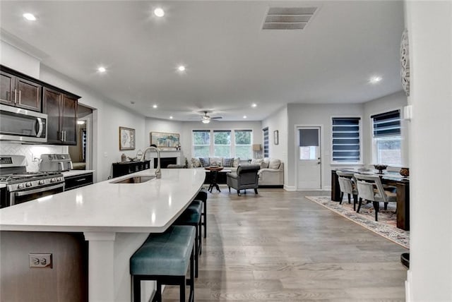 811 Pineberry Ct, Grayson, GA 30017 - kitchen with stainless steel appliances, a sink, light wood finished floors, dark brown cabinetry, and recessed lighting