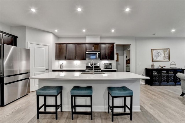 kitchen featuring a breakfast bar area, appliances with stainless steel finishes, decorative backsplash, and a sink