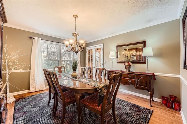 dining space featuring hardwood / wood-style flooring, a chandelier, crown molding, and a textured ceiling