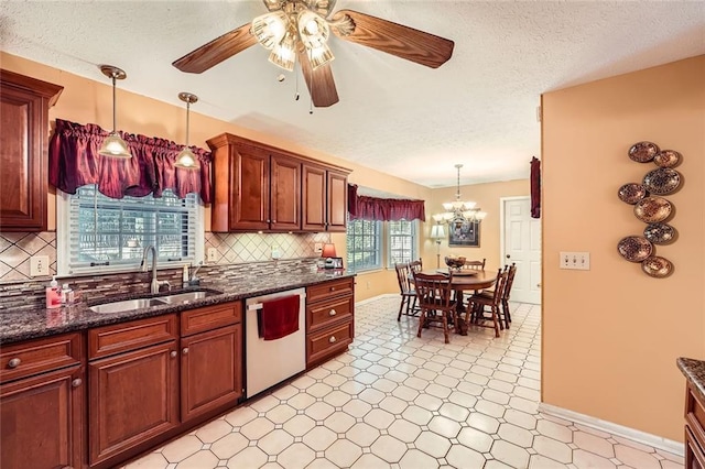 kitchen featuring tasteful backsplash, stainless steel dishwasher, ceiling fan with notable chandelier, sink, and pendant lighting