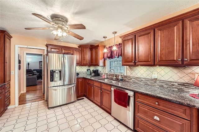 kitchen featuring appliances with stainless steel finishes, ceiling fan, sink, pendant lighting, and dark stone countertops