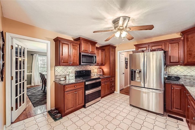 kitchen featuring light hardwood / wood-style floors, backsplash, appliances with stainless steel finishes, and dark stone counters