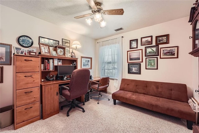 carpeted home office with ceiling fan and a textured ceiling