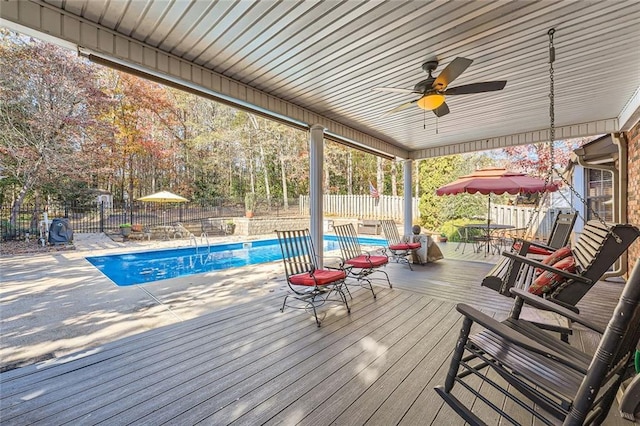 wooden deck with a fenced in pool and ceiling fan