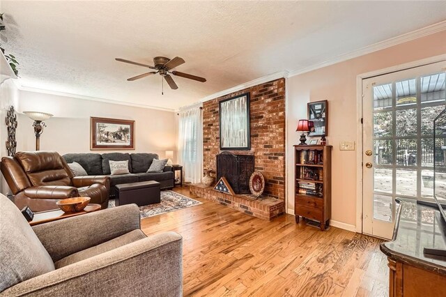 living room featuring crown molding, ceiling fan, a textured ceiling, and light wood-type flooring