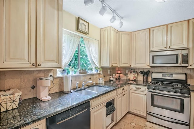 9760 Loblolly Ln, Roswell, GA 30075 - kitchen with appliances with stainless steel finishes, a sink, cream cabinetry, dark stone counters, and rail lighting