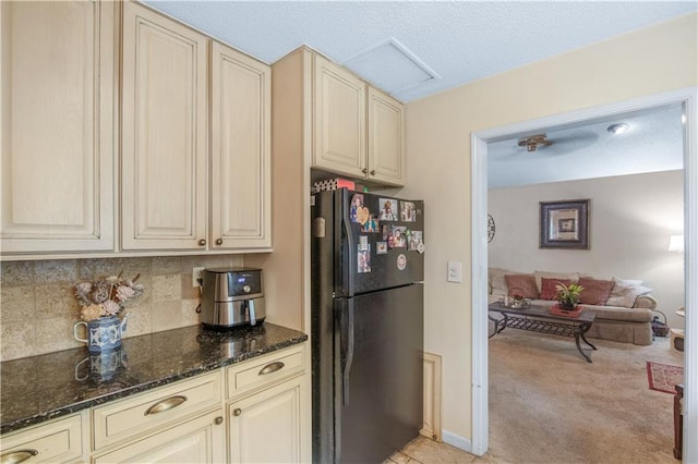 9760 Loblolly Ln, Roswell, GA 30075 - kitchen with freestanding refrigerator, cream cabinets, decorative backsplash, dark stone counters, and light colored carpet