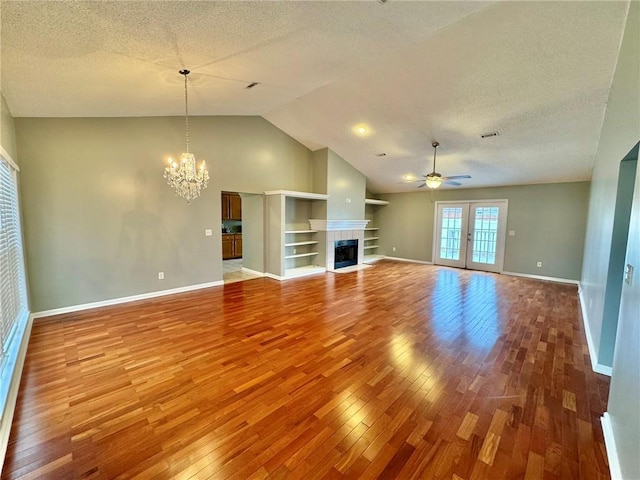 unfurnished living room featuring a textured ceiling, ceiling fan with notable chandelier, wood-type flooring, and a tile fireplace