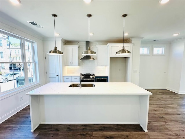 kitchen with dark wood-type flooring, visible vents, an island with sink, and decorative backsplash