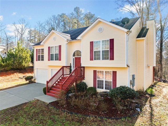 split foyer home featuring a garage, concrete driveway, and a chimney