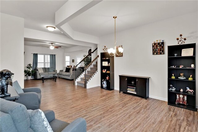 living room featuring ceiling fan with notable chandelier and hardwood / wood-style flooring