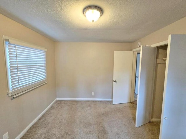 unfurnished bedroom with a closet, a textured ceiling, and light carpet