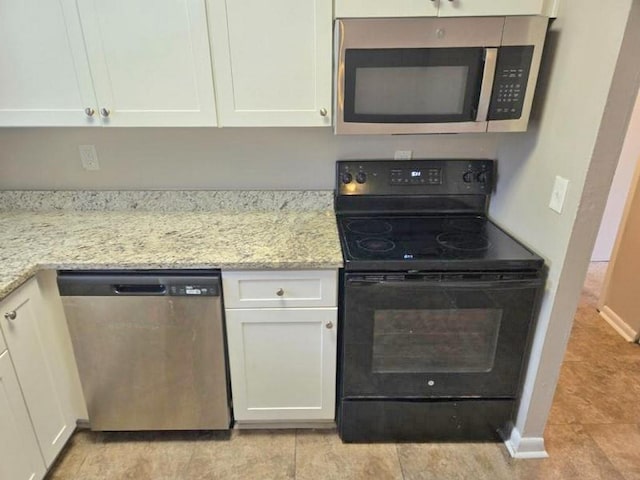 kitchen with light stone countertops, appliances with stainless steel finishes, and white cabinetry