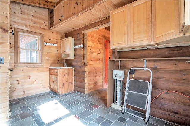 clothes washing area with wooden walls, sink, and dark tile flooring