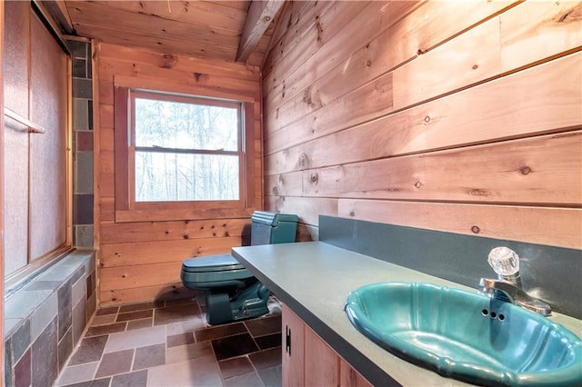 bathroom with toilet, wooden ceiling, vanity, wooden walls, and tile flooring