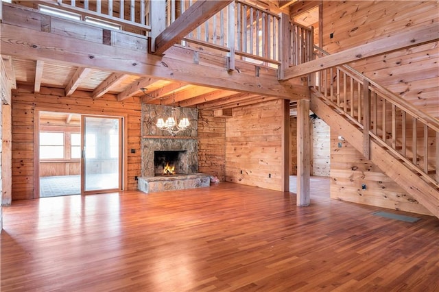 unfurnished living room with wooden walls, an inviting chandelier, wood-type flooring, and a fireplace