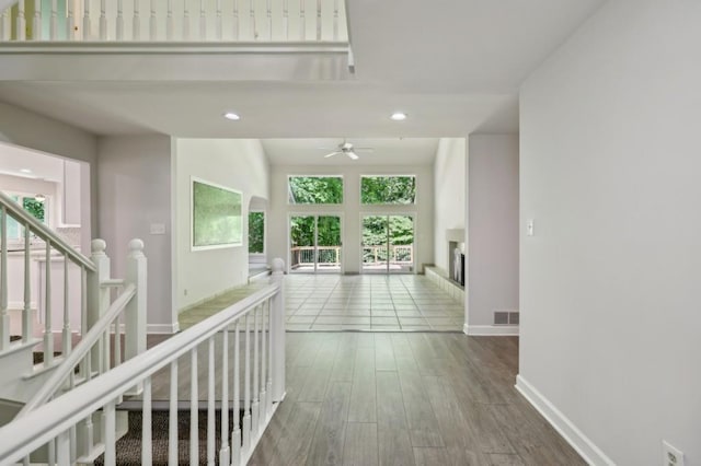 corridor featuring wood finished floors, plenty of natural light, baseboards, and recessed lighting