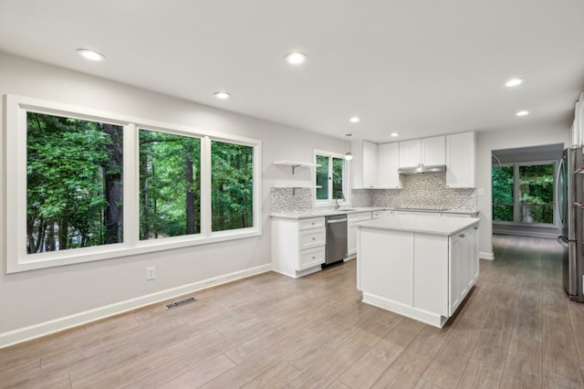 kitchen featuring stainless steel appliances, under cabinet range hood, light countertops, white cabinetry, and tasteful backsplash