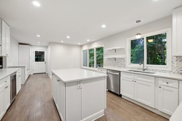 kitchen featuring dishwasher, a sink, a kitchen island, decorative backsplash, and recessed lighting