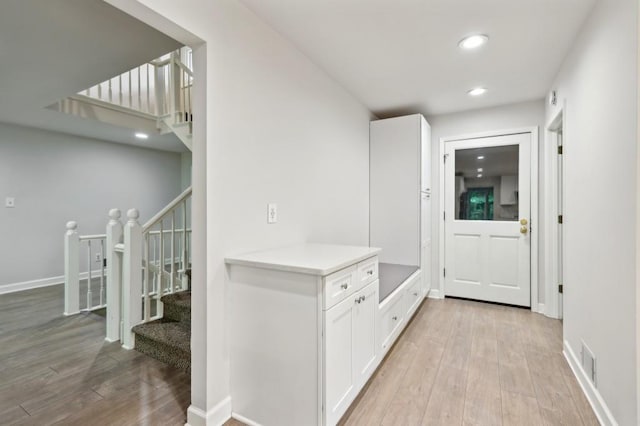 hallway featuring light wood-type flooring, stairs, recessed lighting, and baseboards
