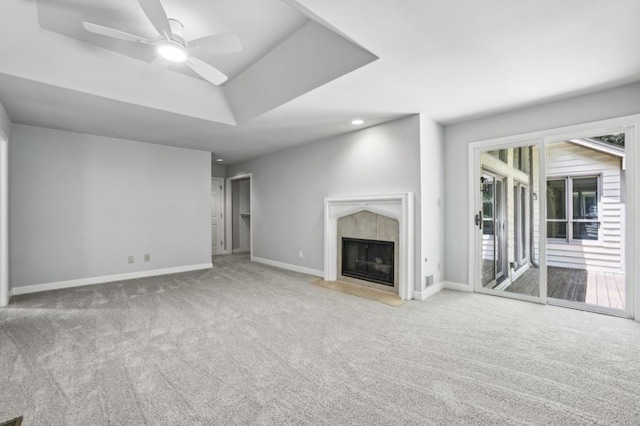 unfurnished living room featuring carpet flooring, a tile fireplace, a ceiling fan, and baseboards