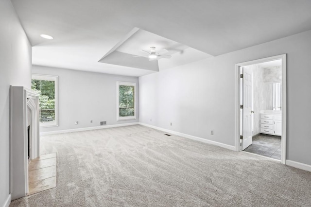 unfurnished bedroom with carpet floors, multiple windows, baseboards, and a fireplace with raised hearth