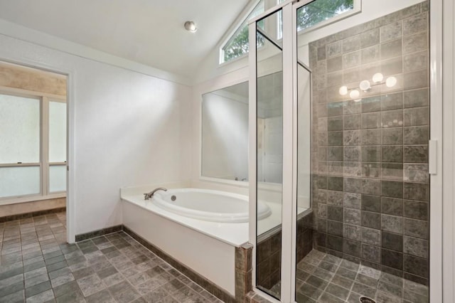 bathroom featuring a shower stall, a bath, vaulted ceiling, and stone finish flooring