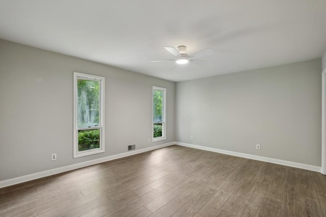 spare room with a ceiling fan, baseboards, and dark wood-style floors