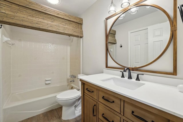 bathroom featuring wood finished floors, toilet, vanity, and shower / tub combination