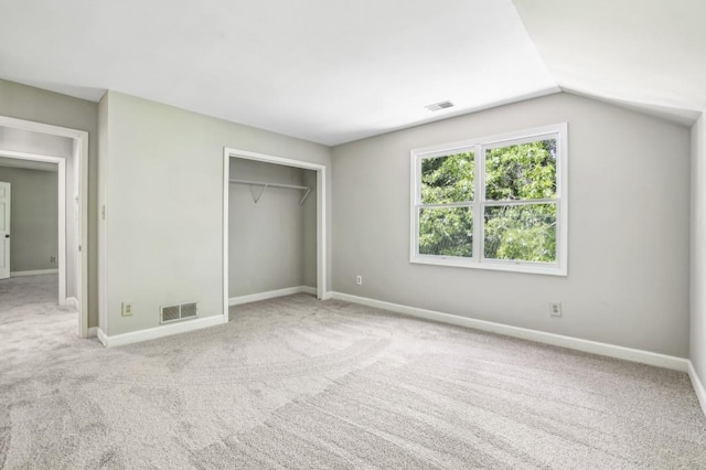 unfurnished bedroom featuring carpet flooring, a closet, baseboards, and lofted ceiling