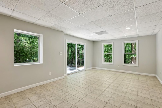 spare room featuring a drop ceiling, plenty of natural light, baseboards, and recessed lighting