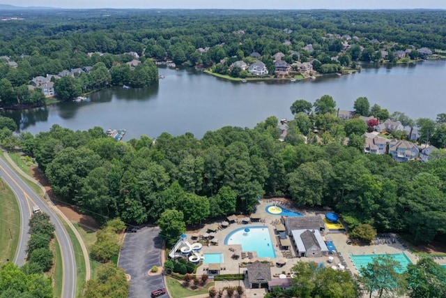 bird's eye view of a heavily wooded area, a pool area, and a large body of water