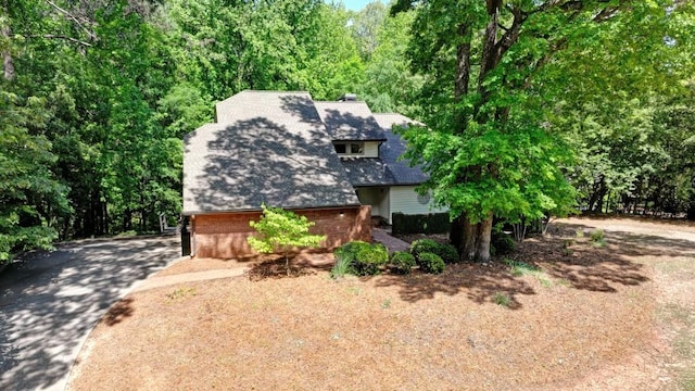 view of front of property with driveway, a shingled roof, and brick siding