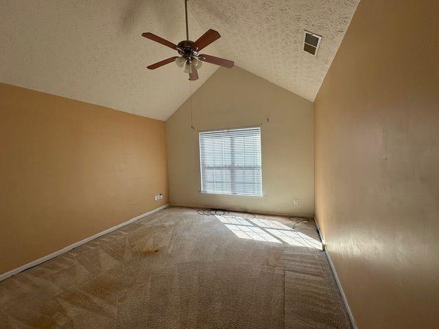 carpeted spare room with ceiling fan, high vaulted ceiling, baseboards, and a textured ceiling