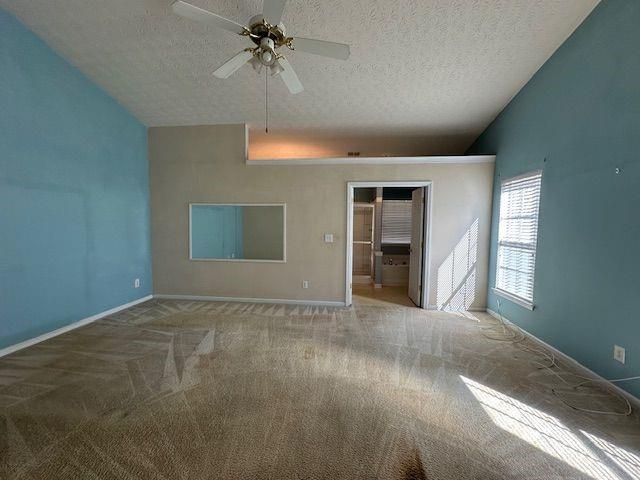 unfurnished bedroom with vaulted ceiling, a textured ceiling, baseboards, and carpet floors