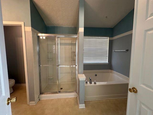 full bath featuring a shower stall, a textured ceiling, toilet, and a garden tub