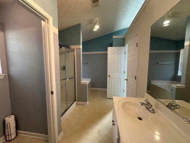 full bath featuring baseboards, lofted ceiling, a shower stall, a textured ceiling, and a bath