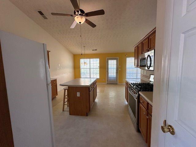 kitchen with visible vents, a kitchen breakfast bar, a center island, appliances with stainless steel finishes, and light countertops