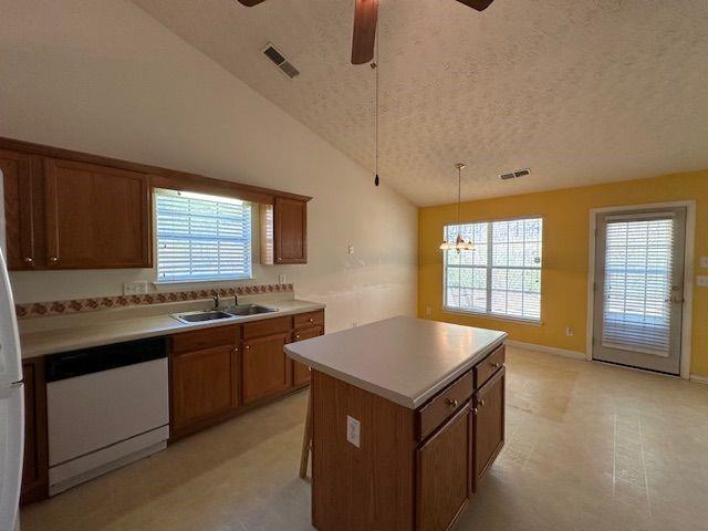 kitchen featuring dishwasher, visible vents, brown cabinets, and a sink