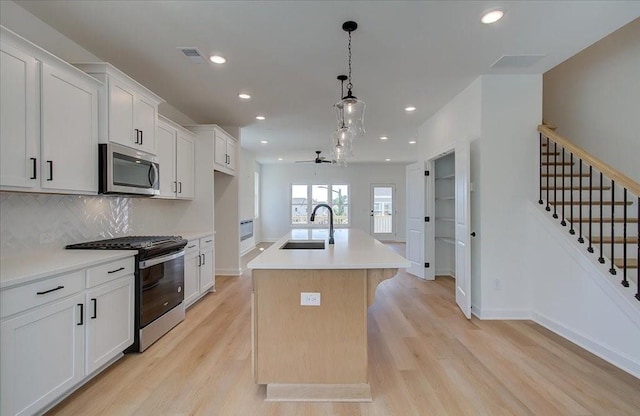 1919 Deco Dr, Kennesaw, GA 30144 - kitchen featuring appliances with stainless steel finishes, light wood-type flooring, a center island with sink, recessed lighting, and light countertops