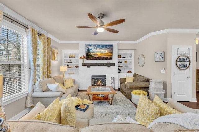 living room with ceiling fan, hardwood / wood-style floors, ornamental molding, a large fireplace, and built in shelves