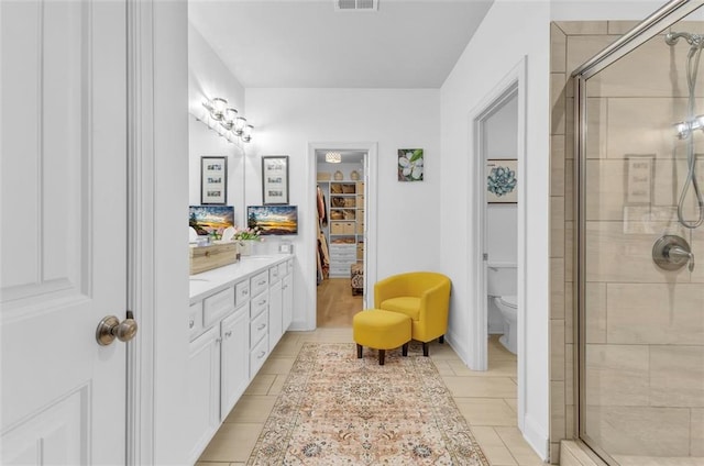 bathroom with tile patterned flooring, vanity, toilet, and a shower with shower door