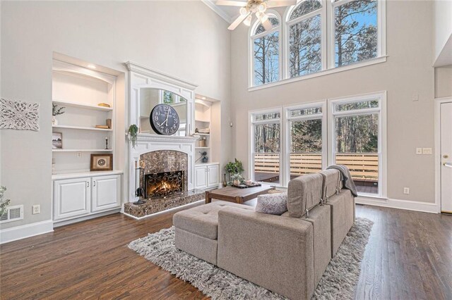 living area featuring built in features, dark wood finished floors, a high end fireplace, and baseboards